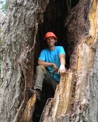 Fred Grimshaw looking through a hollow log